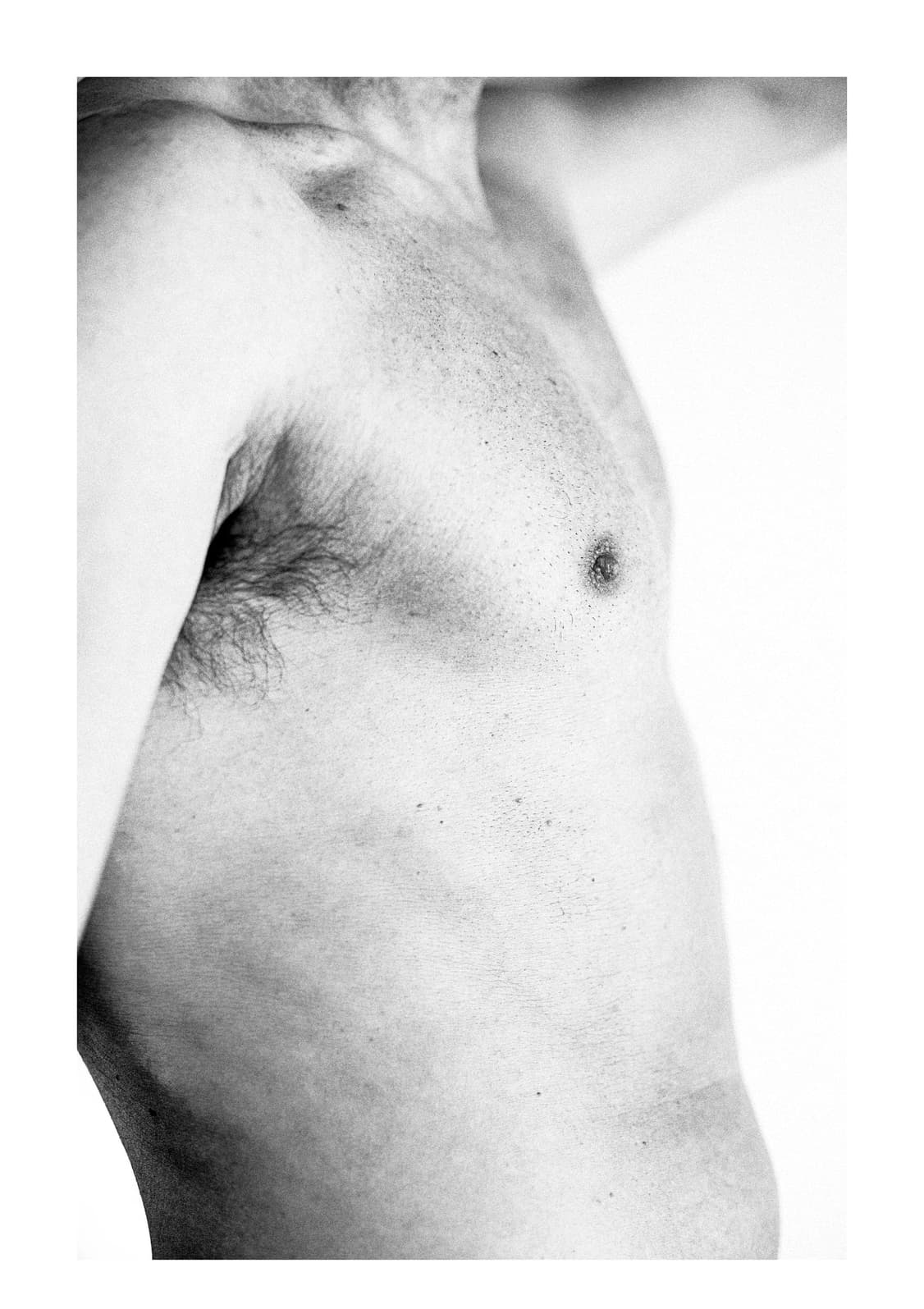 Torso masculino desnudo de perfil con el brazo alzado, sobre fondo claro